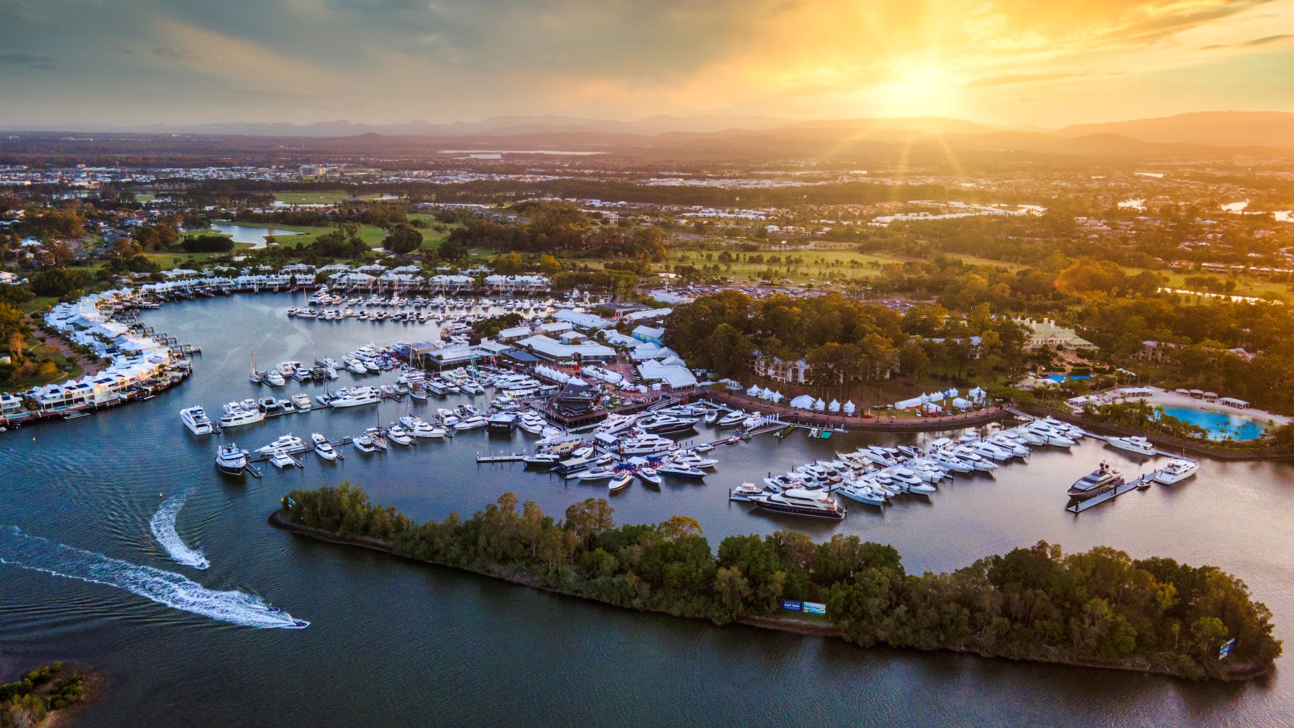 Ariel view of Sanctuary Cove Marina as the sun sets in the distance.